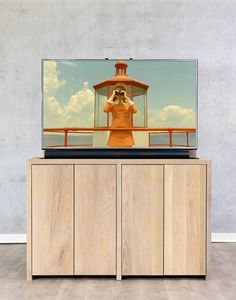 a television on top of a wooden cabinet in front of a wall with an image of a person taking a picture