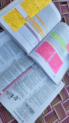 an open book with sticky notes on it sitting on top of a woven table cloth