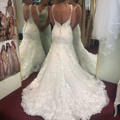 a woman in a wedding dress looking at herself in the mirror with her back to the camera