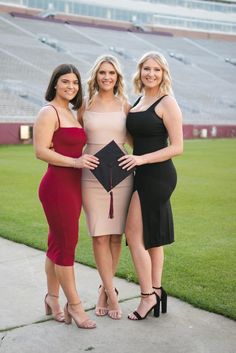 three women pose for a photo in front of an empty stadium