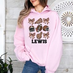 a woman wearing a pink hoodie that says lewis with footballs and bows on it