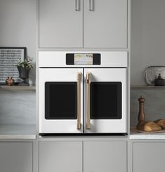 a kitchen with gray cabinets and gold handles on the double ovens in the wall