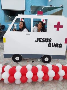 two women sitting in the back of a truck decorated with red and white balloons,