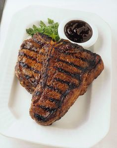 grilled steak and sauce on a white plate