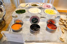 an assortment of condiments are displayed in bowls on a table with oysters