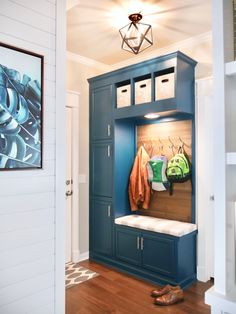 an entryway with blue cabinets and shoes on the bench, bookshelf in the background