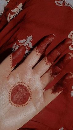 a woman's hand painted with red and white designs on it, sitting on a bed