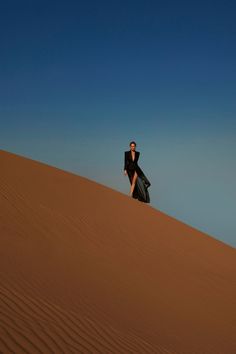 a man sitting on top of a sand dune