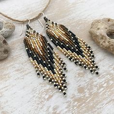 a pair of beaded earrings sitting on top of a table next to some rocks