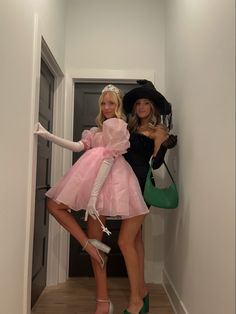 two women dressed up in costumes and hats posing for the camera while holding umbrellas