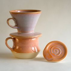 three ceramic cups stacked on top of each other with one cup in the middle and another sitting next to it