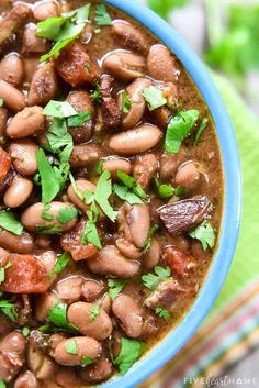 a blue bowl filled with beans and cilantro on top of a green cloth