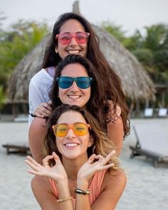 three women in bikinis and sunglasses posing for the camera with their arms around each other