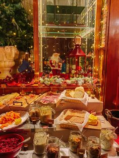 a table filled with lots of food on top of a white table covered in lights