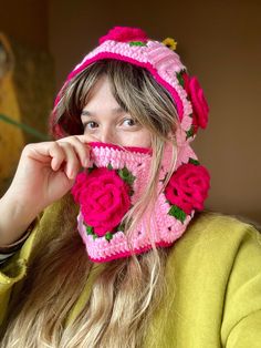 a woman with long hair wearing a pink knitted hat and flowered mittens