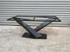 a black metal table sitting on top of a cement floor next to a garage door