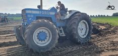 a man driving a tractor on top of a dirt field