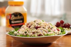 a bowl of chicken salad next to a bottle of mayonnaise on a table