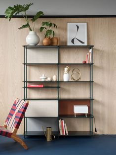 a chair sitting in front of a book shelf filled with books and vases on top of it