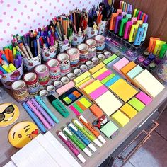 the table has many different colored pens and markers on it, along with other stationery items