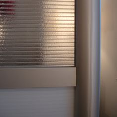 an open window with blinds on the side of it and a red light in the background