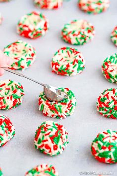 someone is decorating christmas cookies with icing and sprinkles on a baking sheet