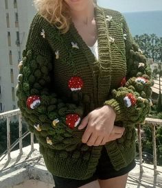 Here is a mushroom cardigan knitted with green yarn, all handmade, with mushroom motifs embroidered with red yarn and white daisy embroideries: This special cardigan is knitted with carefully selected green yarns. The mushroom motifs on the cardigan are carefully embroidered with red threads. These motifs are inspired by nature and add a unique touch to the cardigan. However, white daisy embroideries gracefully appear on the cardigan. Daisies provide beautiful details that add vibrancy and elegance to the cardigan. These special handmade embroideries emphasize the elegance and aesthetics of the cardigan. This cork cardigan is the perfect option for those who are stylish and on-trend. It allows you to get a stylish and eye-catching look both in daily wear and special events. The green color Green Knitted Acrylic Cardigan, Green Knitted Cardigan For Fall, Casual Green Handmade Cardigan, Green Knitted Cardigan For Spring, Green Crochet Cardigan For Fall, Mushroom Cardigan, Green Knitted Cardigan, Long Sweaters For Women, Green Yarn