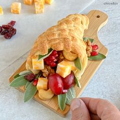 a pastry with fruit and nuts is on a cutting board next to cranberries