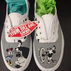 a pair of shoes with mickey mouse painted on the side and green tissue paper sticking out of them