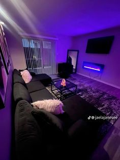 a living room filled with black furniture and purple lighting on the walls, along with a flat screen tv