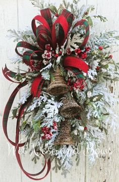 a christmas wreath hanging on the side of a wooden wall with red and green ribbons