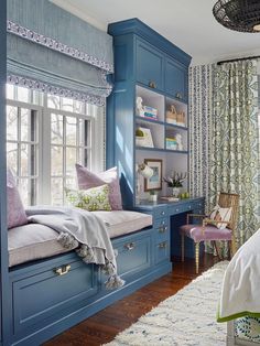 a bedroom with blue walls and built - in bookshelves, window seat, and rug on the floor