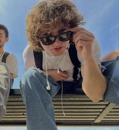 two young men sitting on a bench wearing sunglasses