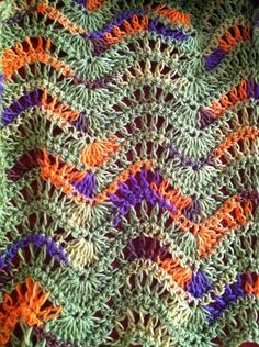 a crocheted blanket with orange, purple and green designs on it's edges