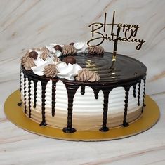 a birthday cake with chocolate icing and white frosting is on a gold plate