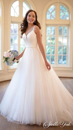 a woman in a white wedding dress posing for the camera with flowers on her bouquet