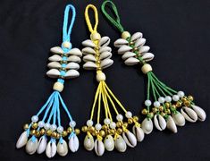 four necklaces with shells and beads hanging from them on a black background, one is white the other is blue