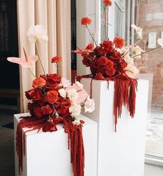 two white vases with red and pink flowers in them sitting on top of each other