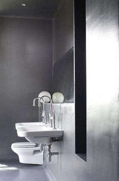 a white toilet sitting next to a sink in a bathroom under a window on the side of a wall