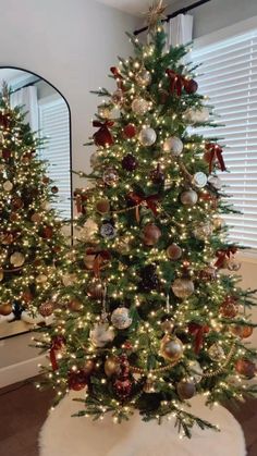 two christmas trees with lights and ornaments on them