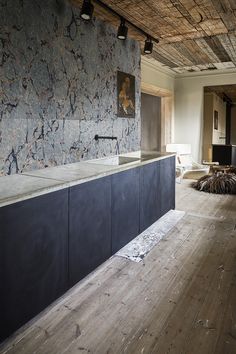 an empty room with wooden floors and white tiles on the wall, along with black cabinets