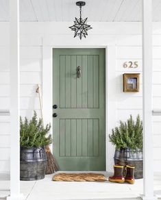 the front door is painted green and has two potted plants