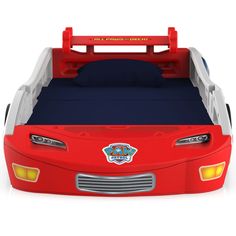 a red toy car bed with blue sheets and pillows on the top, in front of a white background