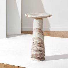 a marble pedestal sitting on top of a hard wood floor next to a white wall