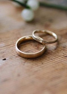 two wedding rings sitting on top of a wooden table