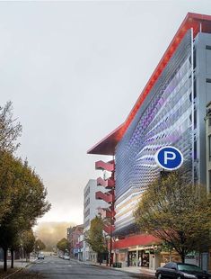 an empty street in front of a building with a parking sign on it's side