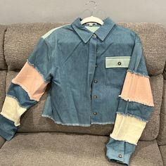 a blue jean shirt with two patches on the sleeves and one patch in the back