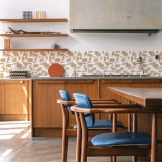 a kitchen with wooden cabinets and blue chairs next to a stove top oven in the center