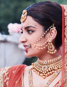 a woman wearing an elaborate gold necklace and headpiece with jewelry on her face,