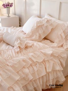 a bed with ruffled sheets and pillows on it